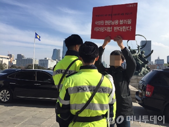 시민단체 '나눔문화' 회원 김모씨(31)가 지난 23일 국회 본관 앞에서 피켓을 들고 시위를 하던 중 경찰의 제지를 받고 있다./ 사진제공=나눔문화