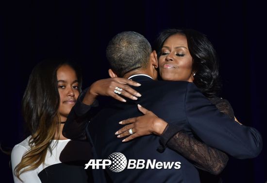 버락 오바마 미국 대통령이 10일(현지시간) 시카고에서 고별연설을 마치고 장녀 말리아가 지켜보는 가운데 부인 미셸 여사와 포옹하고 있다./사진=AFP