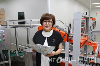 포장 자동화 설비 앞에서 생산된 제품을 들고 있는 김명신 대표