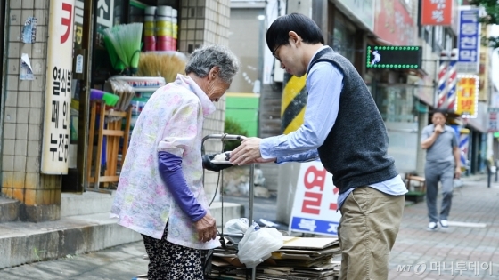 폐지 줍는 노인에게 떡을 전달하며 이야기를 나누고 있는 러블리페이퍼 기우진 대표 /사진=이상봉 기자