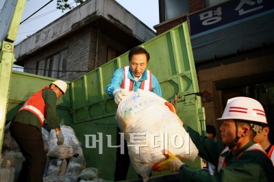 ▲이명박 후보가 청소차 위에서 수거한 쓰레기 봉투를 받아 올리고 있다.