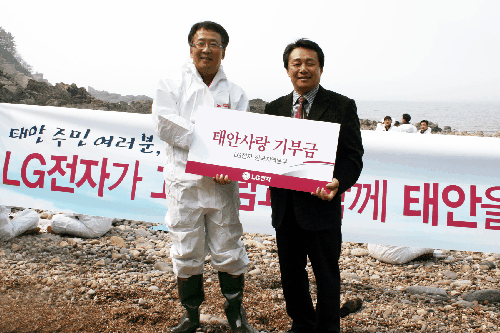 ▲태안군 소원면 파도리 지역 기름제거 복구 현장에서 LG전자 한국지역본부장 박석원 부사장(왼쪽)이 전상욱 충청남도 건설교통국장에게 고객과 함께 모은 '태안사랑 기부금' 4억 원을 전달하고 있다. 