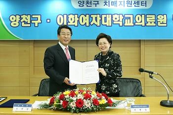 ↑추재엽 서울 양천구청장(왼쪽)과 서현숙 이화여자대학교 의무부총장 겸 의료원장이 치매지원센터 위 수탁기관 협약서를 교환하고 있는 모습.