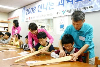 LG화학 기술연구원 소속 연구원들이 24일 대전 소재 아동복지시설 자혜원을 찾아 원아들과 나무와 낚시줄로 전기기타를 만들어보고 있다. 