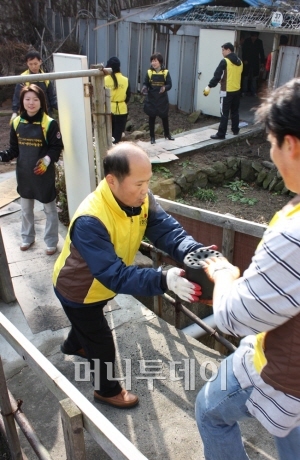 ▲김연배 뉴코아 이사(가운데)가 지난2일 과천에서 독거노인 가정에 줄 연탄을 나르고 있다.