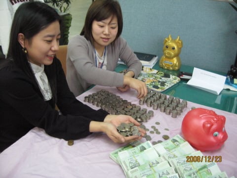 ↑노송동 동사무소 직원들이 화단에서 발견한 ‘전주의 얼굴없는 천사’의 성금액을 세고 있다.  ⓒ사회복지공동모금회