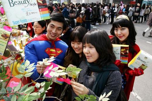 ▲4일 숙명여대 신입생들이 해태제과의 '슈퍼푸드클럽' 제품 출시 기념 새내기 응원이벤트에서 소원을 적은 쪽지를 나무에 걸고 있다. 