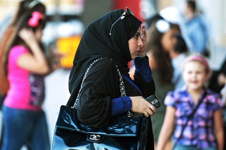 ↑ 쇼핑을 즐기는 검은색 부르카를 두른 이슬람 여성. 그의 손에는 아이폰이 들려있고 명품 가방과 선글라스로 치장하고 있다. 부유한 자국민들의 소비와 관광객의 증가로 두바이 대형 쇼핑몰은 특수를 누리고 있다.   