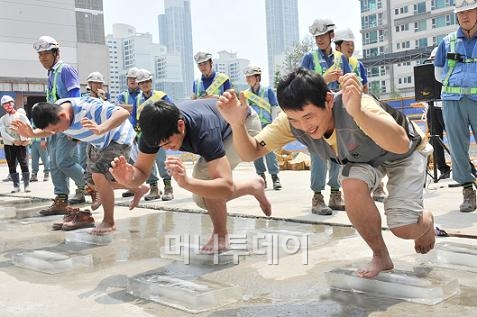 ↑포스코건설 현장 직원들이 '얼음판에서 한발로 오래 버티기' 게임을 하며 즐거워하고 있다. ⓒ포스코건설