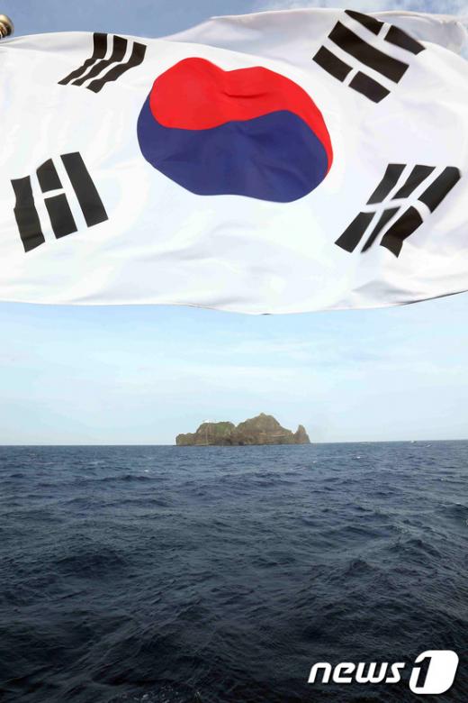 제67주년 광복절을 맞은 15일 오전 독도로 향하는 한국해양대학교 실습선 한나라호에서 바라본 독도 위로 태극기가 휘날리고 있다 ⓒNews1