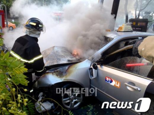 강남소방서(서장 민목영) 소방관들이 11일 서울 강남구 신사동에서 차량을 들이받고 빌딩 앞 볼라드를 넘어 인도의 가로수와 가로등을 들이받은 택시에서 발생한 화재를 진압하고 있다. 사고로 택시기사 안모 씨가 병원으로 이송됐으며 엔진룸 등 소실로 400여 만원의 피해가 발생했다. (강남소방서 제공) 2012.10.11/뉴스1