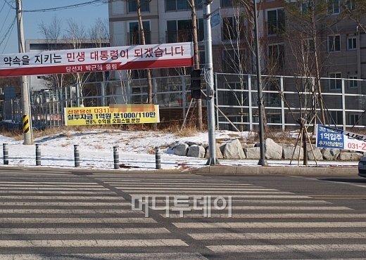 ↑경기 용인 성복동 도로에 오피스텔과 미분양 아파트 분양광고가 붙어 있다. 박근혜 대통령 당선자의 "약속을 지키는 민생 대통령이 되겠습니다"란 현수막 문구와 묘한 조화를 이룬다.ⓒ송학주 기자