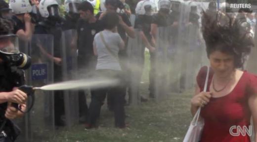 방독면을 쓴 터키 경찰이 한 여성의 얼굴에 최루액을 뿌리고 있다./사진=CNN 동영상 캡처