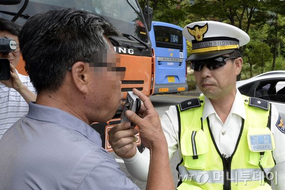  서울 은평경찰서 소속 경찰들이 10일 오후 북한산성 인근에서 대낮 음주단속을 하던 중 한 운전자를 호흡측정기를 통해 음주측정하고 있다. 경찰은 메르스 전염 우려로 인해 자제했던 음주단속을 이날부터 정상화한다고 밝혔다. 2015.7.10/뉴스1  