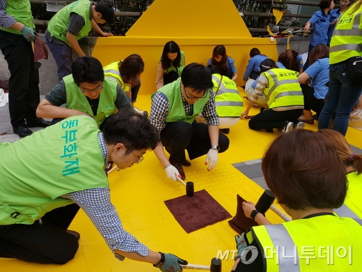 동부화재 임직원과 PA들이 서울 마포구 염리초등학교에서 옐로카펫 설치 작업을 진행하고 있다./사진=동부화재  