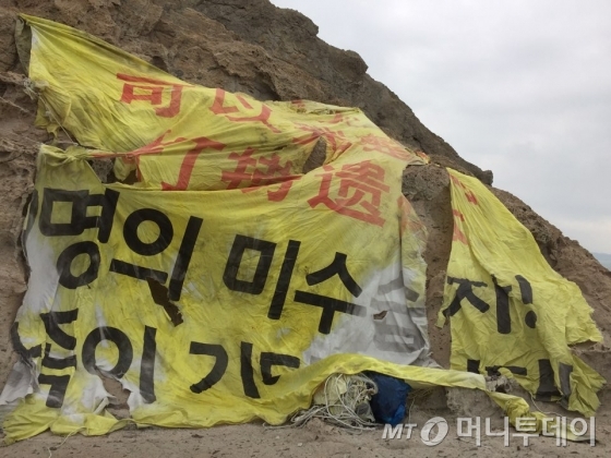 전남 진도군 동거차도 절벽에 걸린 현수막. '9명의 미수습자! 가족이 기다립니다'라고 적혀 있다. 2015년 9월1일 세월호 유가족들이 내걸었다. 이 현수막은 유가족들의 오랜 기다림의 흔적을 고스란히 담고 있다./사진제공=4·16가족협의회 