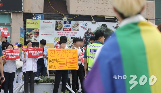  23일 오후 부산 해운대구 구남로 문화광장에서 열린 성 소수자 문화행사인 '부산 퀴어문화축제'에 참가한 참가자가 반대 단체 회원들의 손팻말을 바라보고 있다. 2017.9.23/뉴스1  