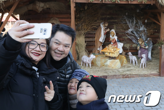 성탄절인 25일 서울 중구 명동성당에 설치된 성탄 구유에서 미사에 참석한 외국인 관광객 가족이 기념촬영을 하고 있다. 2017.12.25/뉴스1 © News1 허경 기자