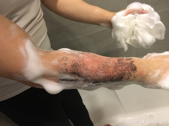 때밀이 타올에 비누를 묻혀 타투를 지워내고 있다. 힘을 줘서 밀자 조금씩 지워졌다./사진=남형도 기자