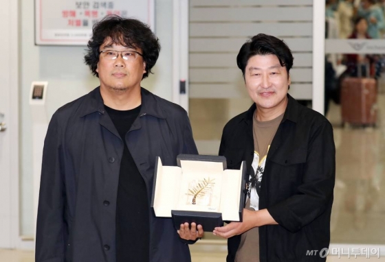 영화 '기생충'으로 한국 영화 최초로 황금종려상의 영예를 안은 봉준호 감독과 주연배우 송강호가 27일 오후 인천국제공항을 통해 귀국하며 상패를 들어보이고 있다. / 사진=김창현 기자 chmt@