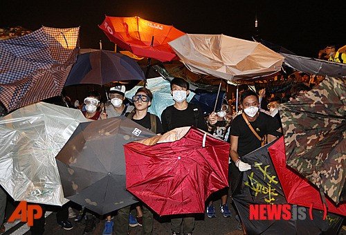홍콩 시위대가 15일 정부청사가 있는 깜종(金鐘) 외곽에 있는 주요 도로에서 우산으로 경찰이 쏜 후추 스프레이를 막고 있다. 홍콩에서 2주 넘게 정치적 위기가 계속되는 가운데 이날 수많은 경찰관들이 정부청사가 있는 이 지역 외곽에 있는 터널에서 시위대 정리 작업에 동원됐다. 시위 진압 장비를 갖춘 경찰관들이 시위대에 후추 스프레이를 뿌려 시위대를 진압하고 지하도 주변에 세워진 바리케이드와 콘크리트 슬래브를 철거했다. 2014.10.15/사진=뉴시스