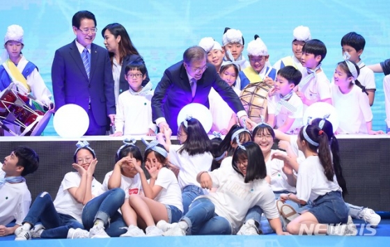 【무안=뉴시스】전신 기자 = 문재인 대통령이 12일 전남 무안군 전남도청에서 열린 전남 블루이코노미 경제비전 선포식에서 참석자들과 함께 대형 블루 이코노미 볼을 터치하는 세리머니를 마친 뒤 선포식 기념공연을 선보인 아이들과 기념촬영을 하고 있다. 2019.07.12. photo1006@newsis.com