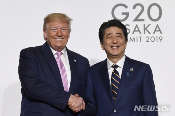 【오사카=AP/뉴시스】28일 일본 오사카에서 주요 20개국(G20) 정상회담이 개막한 가운데 도널드 트럼프 미국 대통령과 아베 신조 일본 총리가 만나 악수하며 기념촬영을 하고 있다. 2019.06.28.