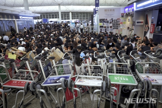 지난 13일 오후 홍콩의 '범죄인 인도 법안(송환법)' 반대 시위대가 공항 내 카트를 쌓아 차벽을 이루며 대규모의 농성을 벌이고 있다. 지난 이틀 동안 탑승 수속이 중단됐던 홍콩국제공항은 14일(현지시간) 오전 업무를 재개한 상황이다. / 홍콩=AP/뉴시스
