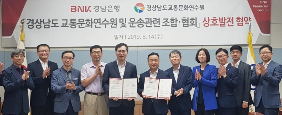 BNK경남은행 한기환 그룹장(사진 오른쪽 여섯번째)이경상남도교통문화연수원 공윤권 원장(사진 오른쪽 일곱번째)을 비롯한 경상남도 내 9개 운송사업조합ㆍ협회 이사장들과 ‘상호 발전 협약’을 체결하고 있다./사진제공=경남은행