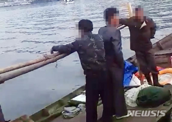 【서울=뉴시스】 삼척 북한 목선 파장이 갈수록 커지고 있는 21일 지난 15일 오전 6시 50분, 삼척항 방파제에 북한 어선이 왔다는 신고에 삼척 파출소 경찰들이 목선을 타고 온 북한 주민들을 조사하고 있다. 해경은 19분이 지난 7시 9분에 첫 보고서를 청와대, 국정원, 합참 등에 북한 어선이 자체 동력으로 삼척항에 입항했다고 보고 했다. 하지만 군은 17일 첫 발표에서 어선 발견 지점을 '삼척항 인근'이라고만 했고, 표류라고 명시해, 자체 동력으로 배가 움직인 것도 숨겨 논란이 되고 있다. 2019.06.21. (사진= 독자 제공) photo@newsis.com