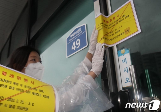 25일 신종 코로나바이러스 감염증(코로나19) 울산 확진자가 4명으로 늘어난 가운데 울산시청 공무원들이 남구 무거동 신천지 울산교회 출입문에 폐쇄명령서를 붙이고 있다. 울산시는 '감염병의 예방 및 관리법 제47조와 제49조에 따라 신천지 울산교회 본관과 부속기관 19곳 등 모두 20곳을 3월9일까지 2주간 폐쇄한다고 밝혔다./사진=뉴스1