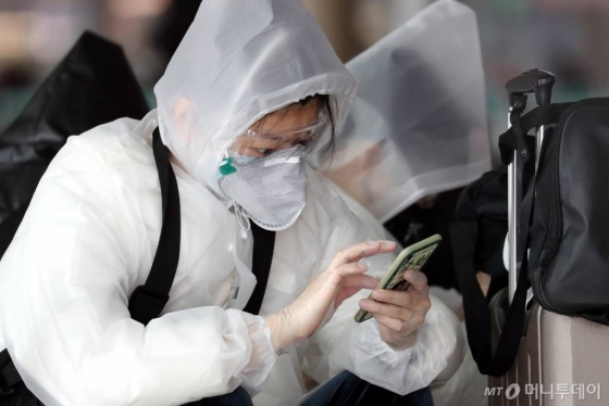 코로나19 국내 확산이 빠르게 진행되고 있는 가운데 26일 인천국제공항 제1터미널 출국장에서 보호 장비를 착용한 중국인들이 휴대전화를 만지고 있다. / 사진=이기범 기자 leekb@