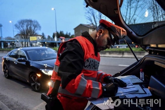 [밀라노=AP/뉴시스]10일(현지시간) 이탈리아 밀라노의 도로에서 한 경관이 밀라노로 진입하는 차량을 검문하고 있다. 신종 코로나바이러스 감염증(코로나19) 확산을 늦추기 위한 최근의 조치에 따라, 한 장소에서 다른 장소로 이동하는 사람들은 업무상 또는  건강상의 이유로 이동한다는 것을 증명해야 한다. 