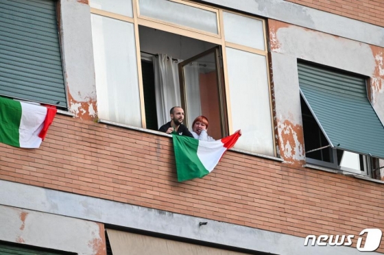 15일(현지시간) 코로나19 확산 방지를 위해 이탈리아 전역에 이동 제한령을 내린 가운데 로마에서 시민들이 서로를 응원하며 연대감을 높이기 위해 발코니에나와 국기를 흔들며 노래를 부르고 있다.  /사진=뉴스1(AFP)