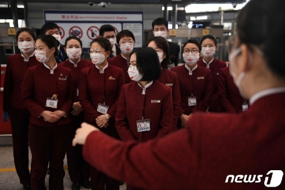 24일 (현지시간) 베이징 공항 체크인 구역에서 코로나 19의 감염을 예방하기 위해 에어 차이나 승무원들이 마스크를 쓰고 모여 있다. © AFP=뉴스1 © News1 우동명 기자