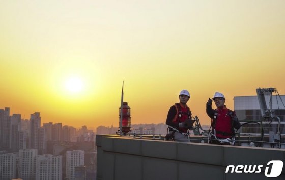 SK텔레콤 홍보모델들이 서울에 위치한 한 빌딩 위에서 5G 기지국을 점검하며 5G 상용화 1주년을 기념해 포즈를 취하고 있다. /사진=뉴스1