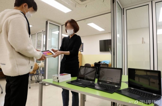 온라인 개학을 하루 앞둔 8일 서울시내 한 중학교에서 교사가 학생에게 대여 스마트기기를 전달하고 있다./사진=김휘선 기자