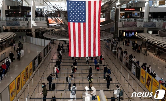 지난 13일 (현지시간) 코로나19 팬데믹 상황 속 뉴욕 퀸즈의 JFK 공항 터미널에서 마스크 쓴 승객들이 거리를 두고 줄을 서 있다. /사진=뉴스1, AFP