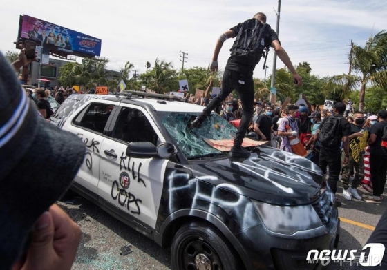(로스앤젤레스 AFP=뉴스1) 우동명 기자 = 30일(현지시간) 캘리포니아주 로스앤젤레스에서 비무장 흑인 남성 조지 플로이드의 백인 경찰 가혹 행위로 숨진 사건에 항의하는 시위대가 경찰 차량을 파손하고 있다. ⓒ AFP=뉴스1