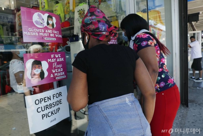 [뉴욕=AP/뉴시스] 8일(현지시간) 미국 뉴욕에서 고객들이 여성복 매장을 들여다보고 있다. 유리창에 매장 수령 서비스(Curbside pickup)만 가능하다고 알리는 종이가 붙어있다. 마스크 착용을 요청하는 종이도 보인다. 뉴욕은 이날 신종 코로나바이러스 감염증(코로나19) 관련 1단계 경제 재개에 돌입했다. 2020.06.09.