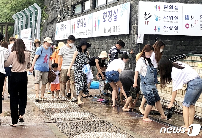 지난 28일 제주 서귀포 중문 해수욕장 입구 수돗가에서 관광객들이 모래를 털고 있다.2020.6.28/뉴스1© News1 홍수영 기자