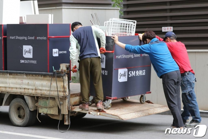 지난 4월 코로나19 영향으로 영업을 종료하는 서울 종로구 SM면세점 앞에서 관계자들이 짐을 옮기고 있다. /사진=뉴스1