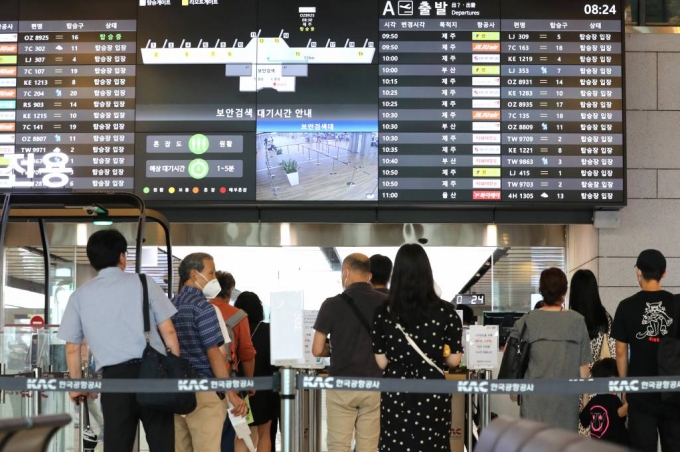 본격적인 휴가철을 맞은 지난 27일 오전 서울 강서구 김포공항 국내선 청사에서 코로나19로 해외 대신 국내여행을 떠나는 여행객들이 탑승장으로 가기 위해 줄을 서고 있다. /사진=뉴시스
