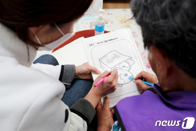 치매안심센터 직원이 코로나19 사태가 장기화에 치매안심 지원센터를 찾아오지 못하는 맞춤형 사례관리자 어르신들을 찾아가 건강 상태를 체크, 치매안심키트와 간단한 식료품을 비롯해 손 소독제, 마스크 등 위생용품을 전달하고 색칠 프로그램을 진행하고 있다. (성동구 제공) ⓒNews1