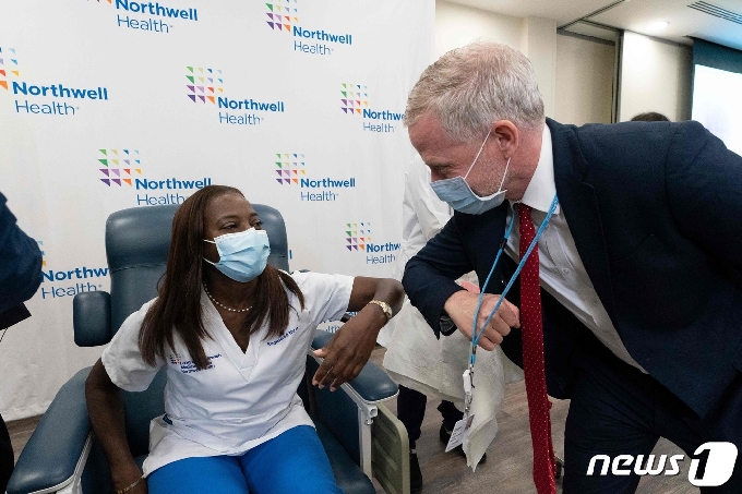 [사진] 홍보 담당자와 팔꿈치 맞대는 미국 첫 백신 접종 간호사