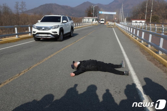 지난 28일 오전 서울 동부구치소에서 신종 코로나바이러스 감염증(코로나19) 확진 판정을 받은 수용자를 태운 버스가 경북 청송군 경북북부 제2교도소로 출발했다는 소식이 전해지면서, 자신을 청송군 주민이라고 밝힌 한 남성이 확진자 수용에 반대하며 도로를 가로막고 누워 있다./사진=뉴스1