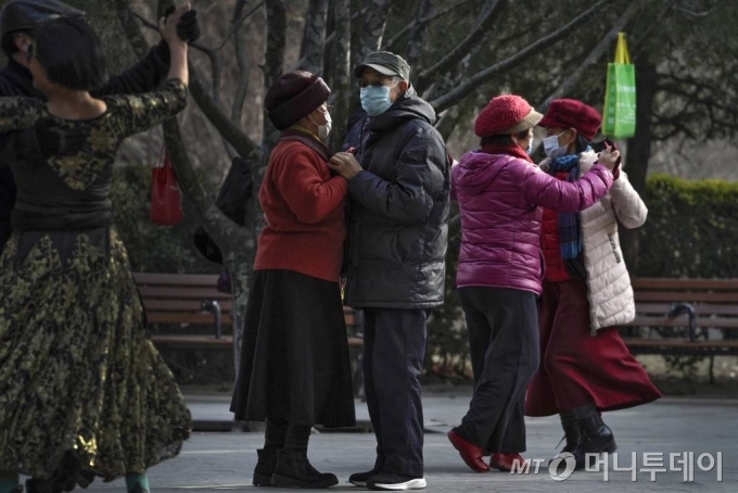 [베이징=AP/뉴시스]12일 중국 베이징의 한 공원에서 코로나19 예방을 위해 마스크를 쓴 사람들이 사교춤을 즐기고 있다. 2021.01.12.