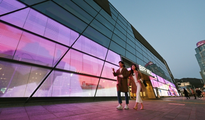 LG전자 모델들이 투명 LED(발광다이오드) 필름이 설치된 부산 '영화의전당' 주변 경관을 소개하고 있다. /사진제공=LG전자