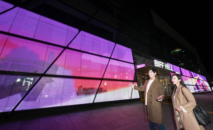 LG전자 모델들이 투명 LED(발광다이오드) 필름이 설치된 부산 '영화의전당' 주변 경관을 소개하고 있다. /사진제공=LG전자