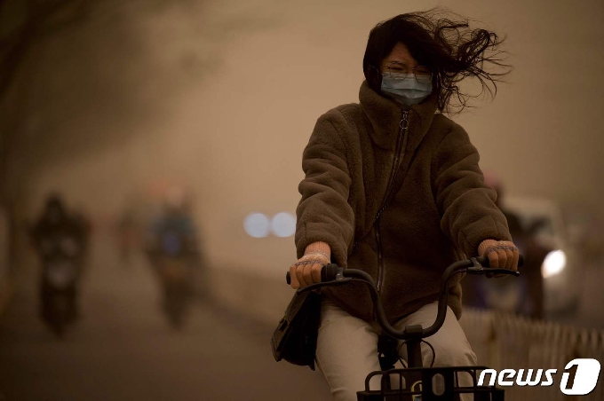 15일 베이징에서 한 여성이 황사 속에서 자전거로 도로를 달리고 있다.  © AFP=뉴스1 © News1 김정한 기자